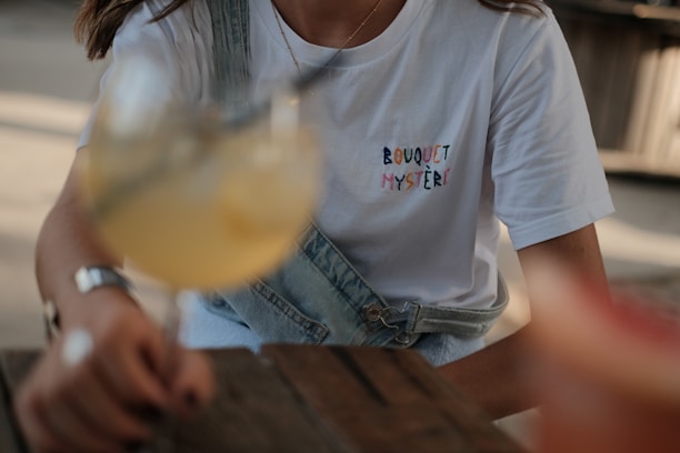 woman in white crew neck t-shirt holding clear drinking glass