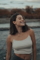 woman in white tank top standing near body of water during daytime