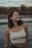 woman in white tank top standing near body of water during daytime