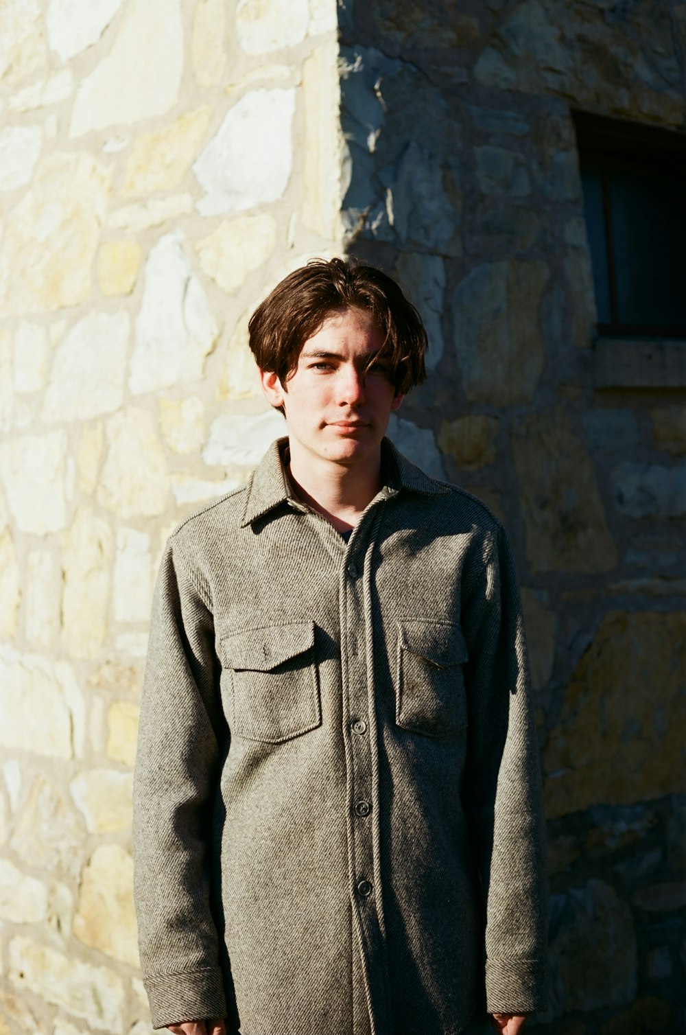 woman in gray coat standing beside gray concrete wall