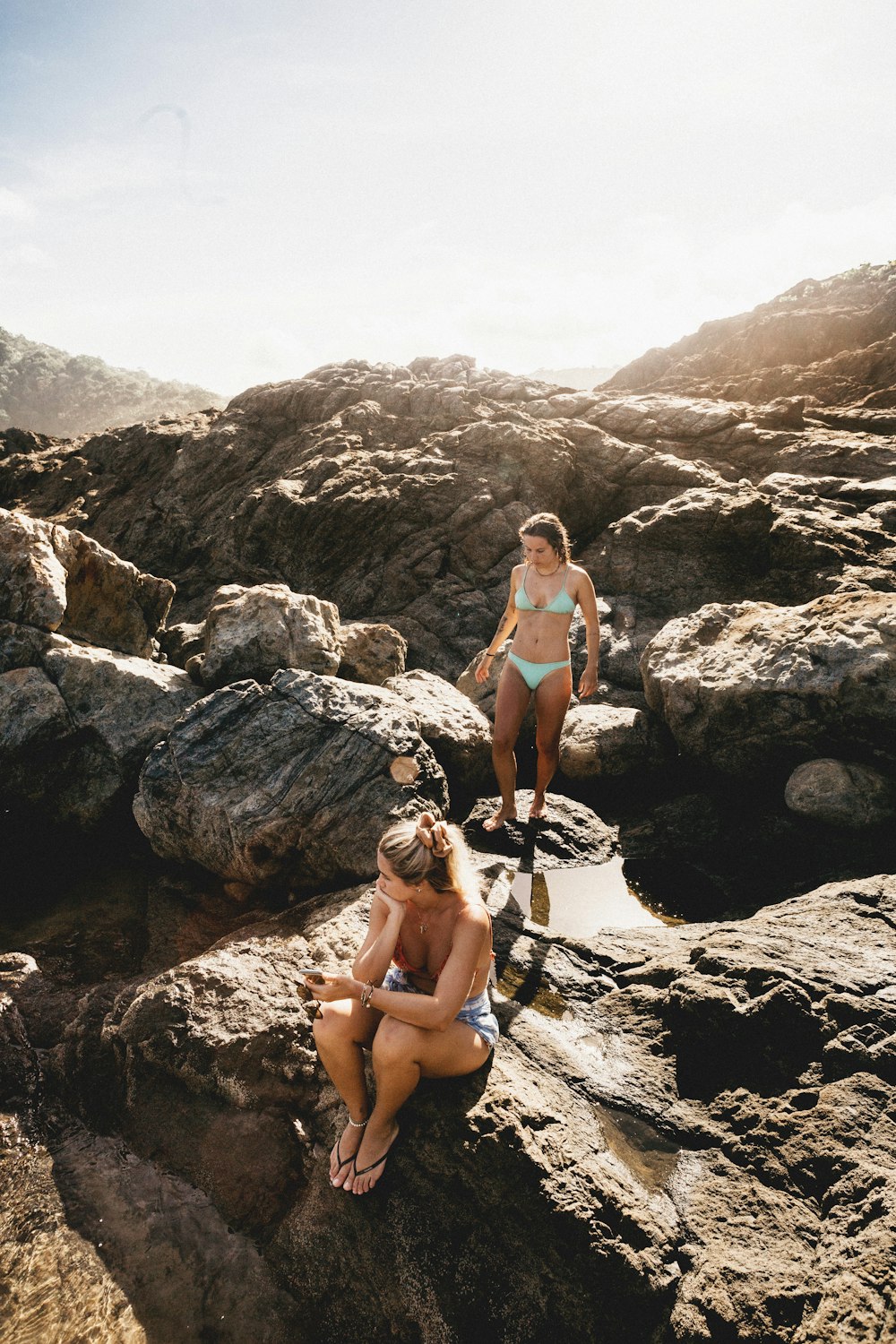 woman in white sports bra and black shorts sitting on rock during daytime