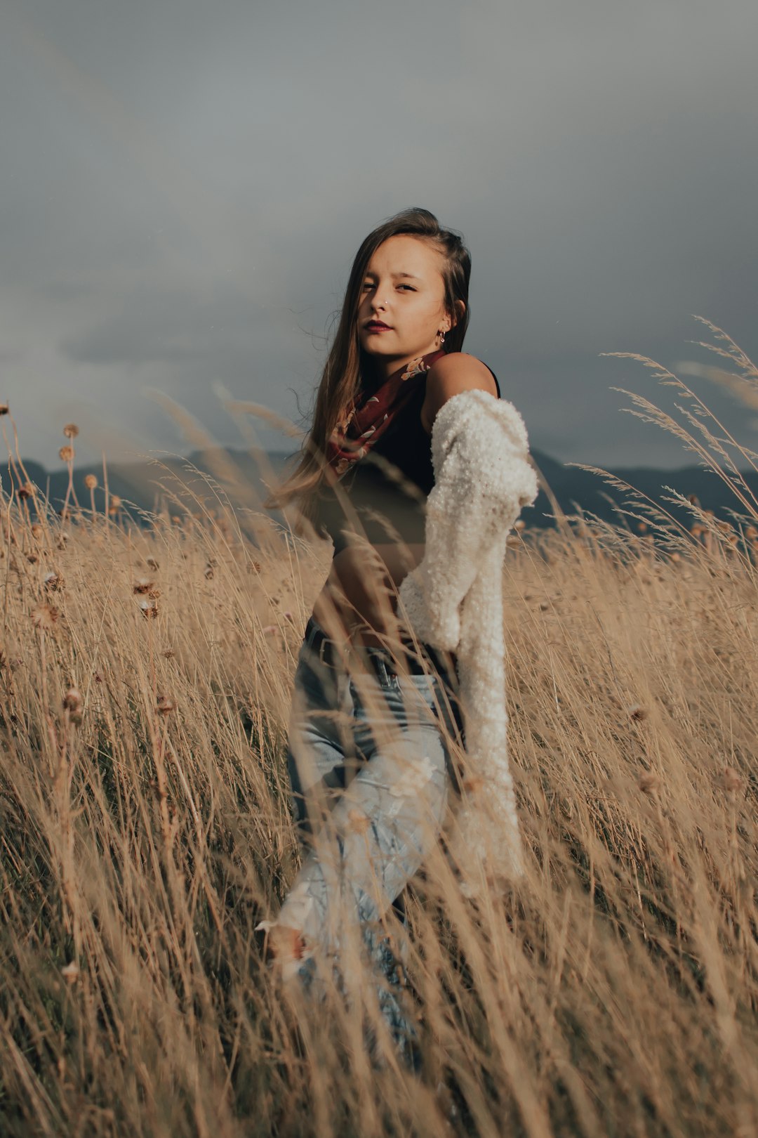 woman in white fur coat standing on brown grass field during daytime