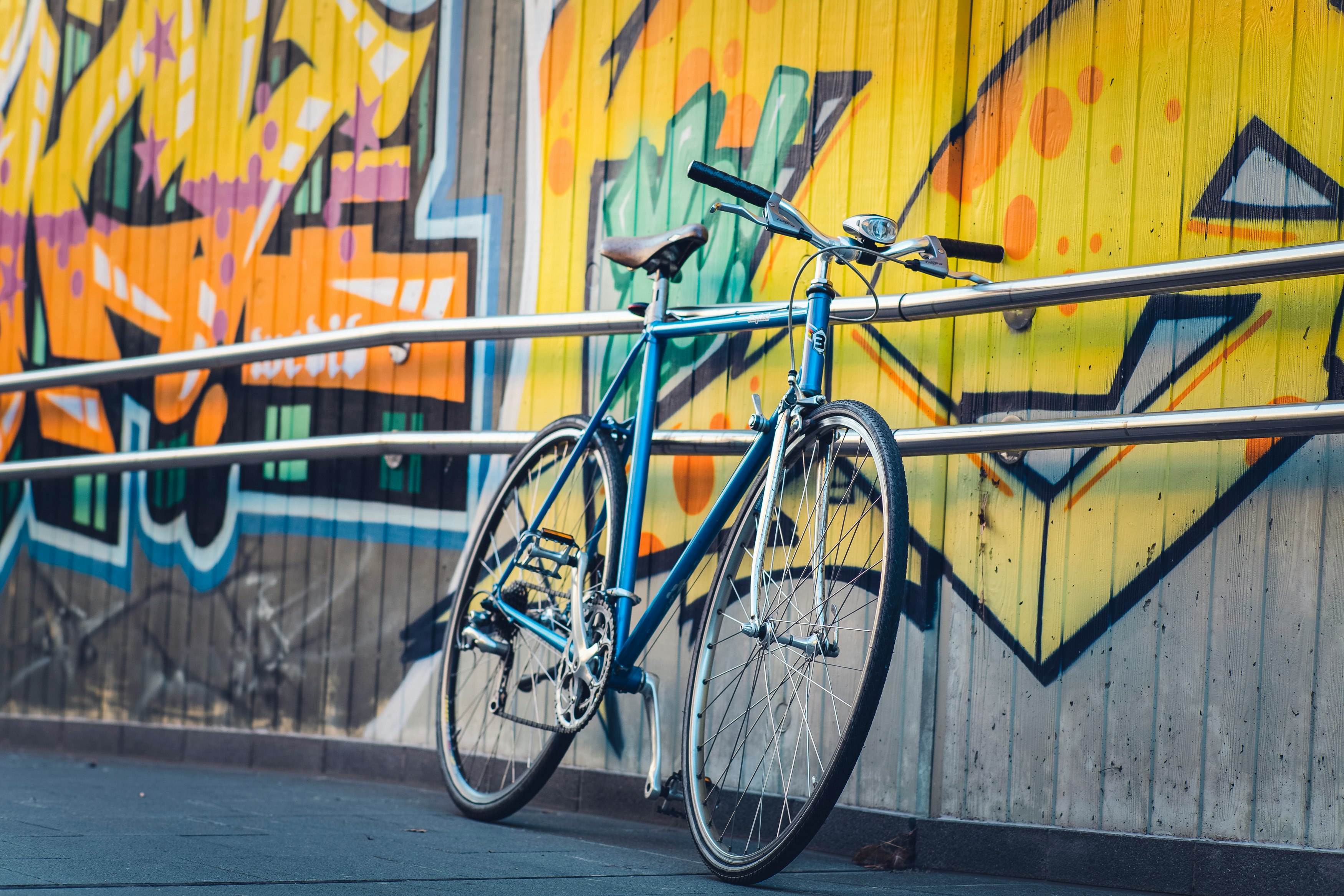 blue city bike parked beside blue metal fence during daytime
