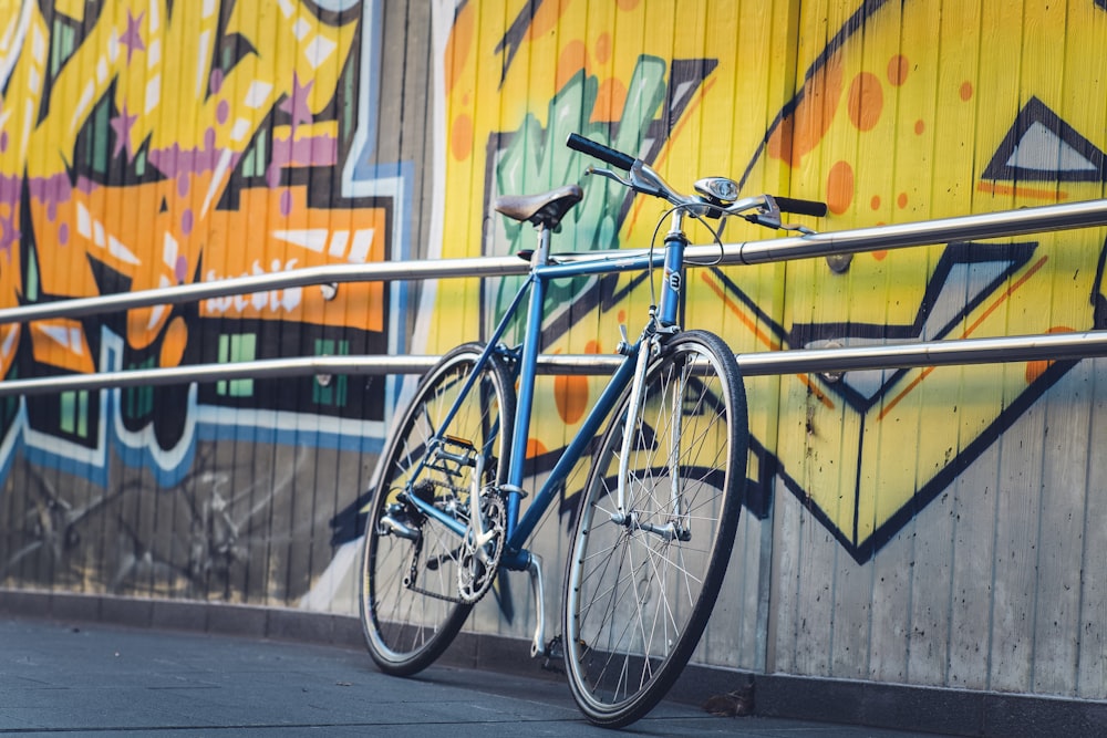 blue city bike parked beside blue metal fence during daytime