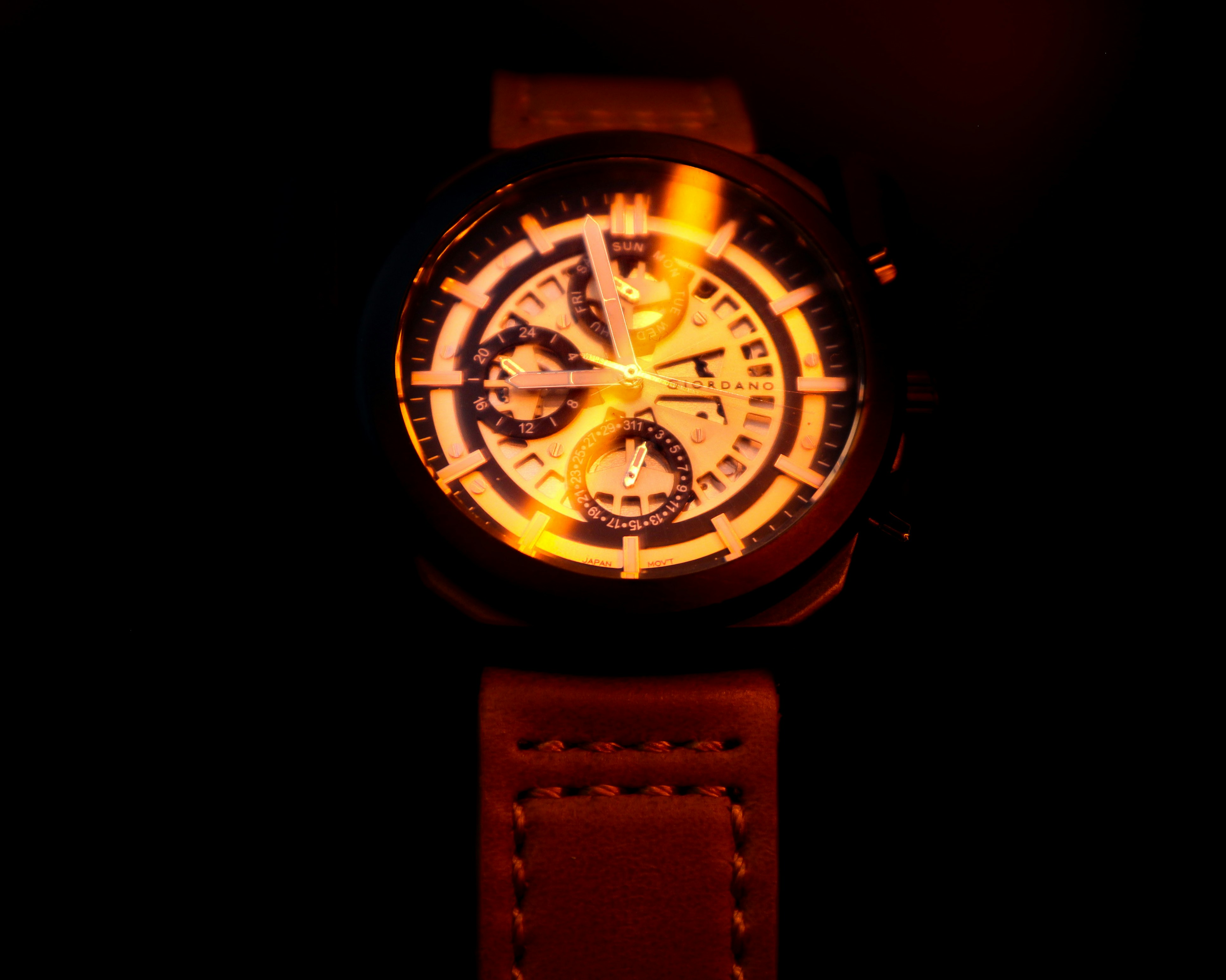 round gold chronograph watch with brown leather strap