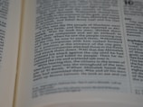 A close-up view of an open book showing readable text. The text is in columns and features headings in bold. The pages appear to be from a religious or historical text, discussing events and figures in a narrative style.