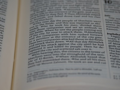 A close-up view of an open book showing readable text. The text is in columns and features headings in bold. The pages appear to be from a religious or historical text, discussing events and figures in a narrative style.
