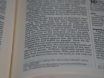 A close-up view of an open book showing readable text. The text is in columns and features headings in bold. The pages appear to be from a religious or historical text, discussing events and figures in a narrative style.