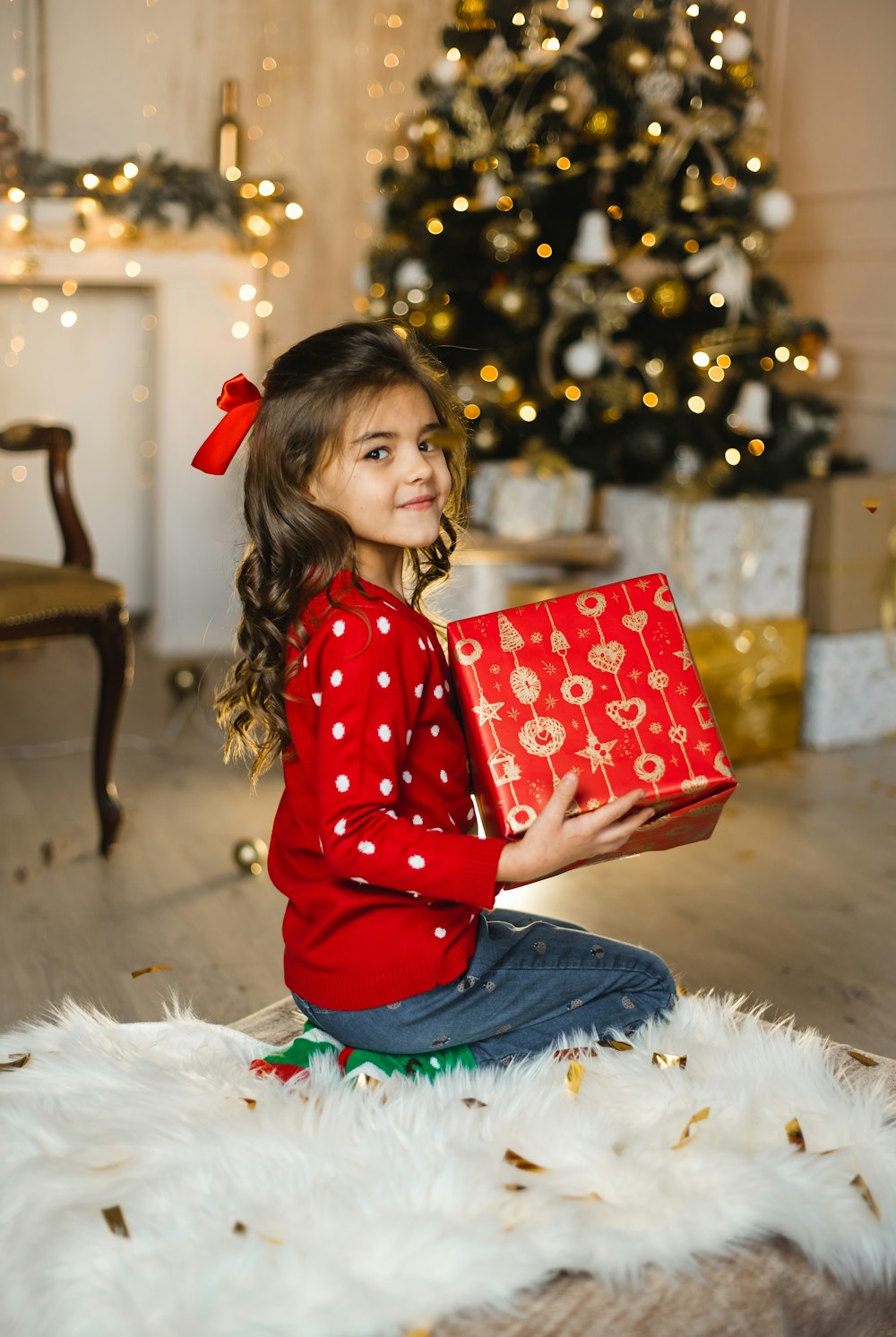 girl in red and white polka dot long sleeve shirt sitting on white fur textile