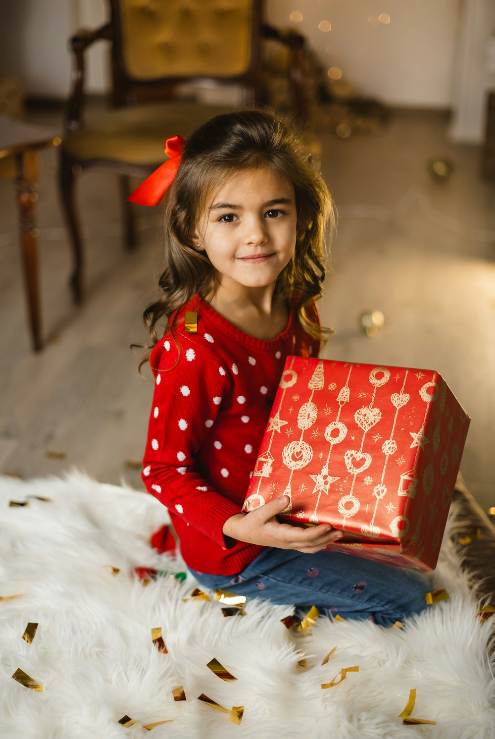 girl in red sweater sitting on white textile