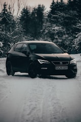 A sleek black sedan waiting outside Kiruna Airport under a snowy sky.