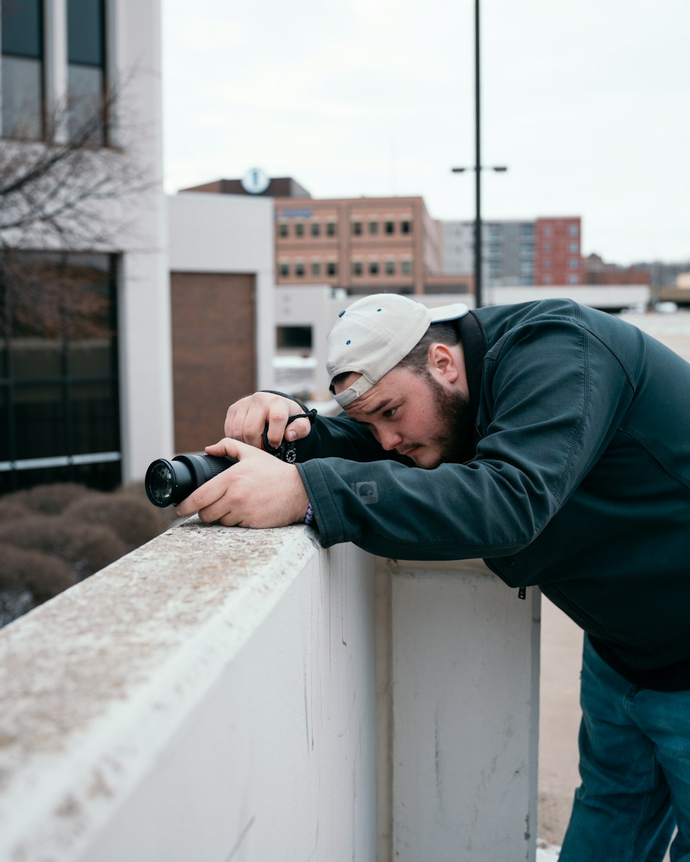 Hombre con sudadera con capucha verde sosteniendo una cámara DSLR negra