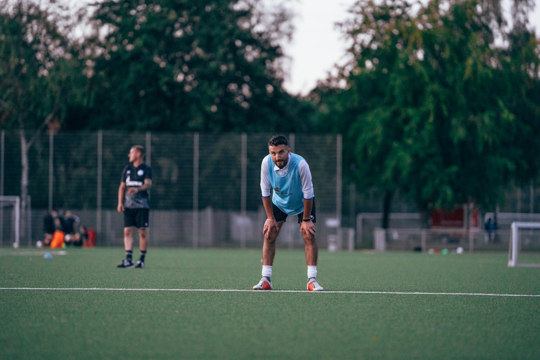 man in blue and white soccer jersey shirt kicking ball during daytime