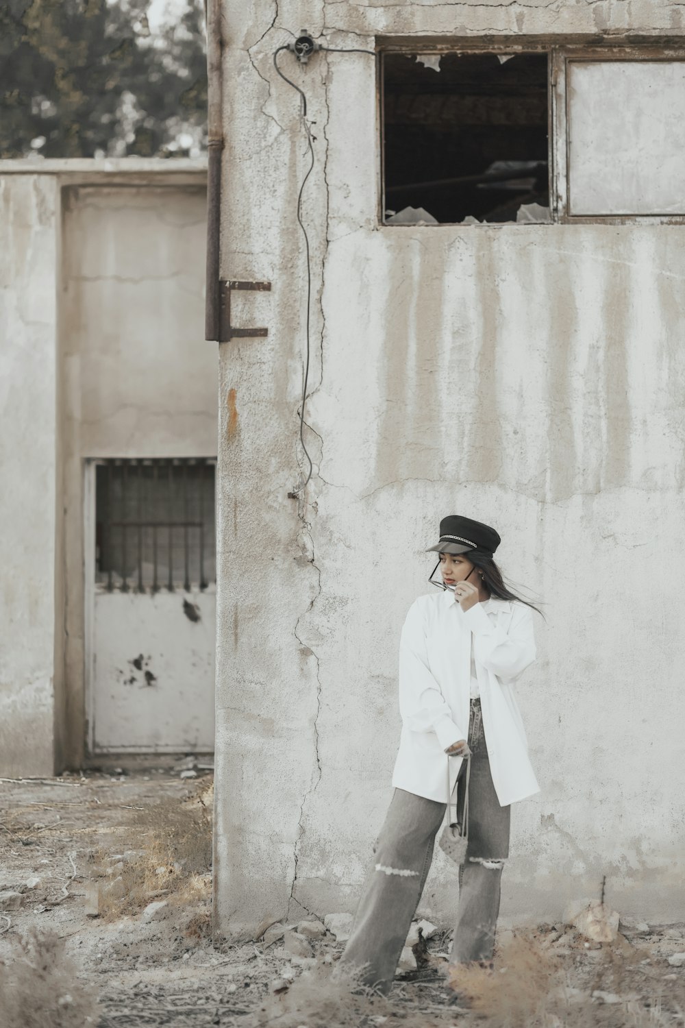 man in white dress shirt and black hat standing in front of white concrete building during