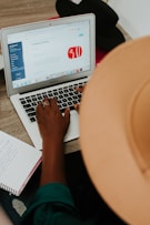 person using macbook air on brown wooden table