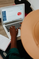 person using macbook air on brown wooden table
