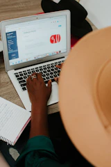 person using macbook air on brown wooden table