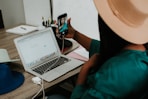 person holding black smartphone near macbook pro