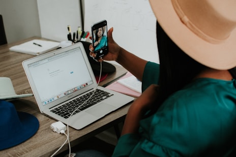 person holding black smartphone near macbook pro