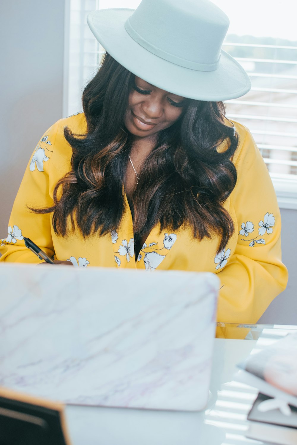 woman in yellow and black floral long sleeve shirt wearing white hat