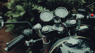 A sleek GPS tracking device installed on a motorcycle dashboard with a blurred forest background.