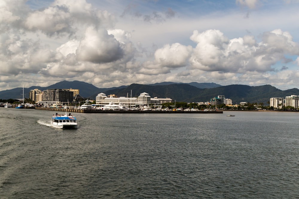 white and blue boat on sea under white clouds during daytime