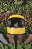 Close-up of a dusty motorcycle helmet resting on a wooden fence beside a rural highway.