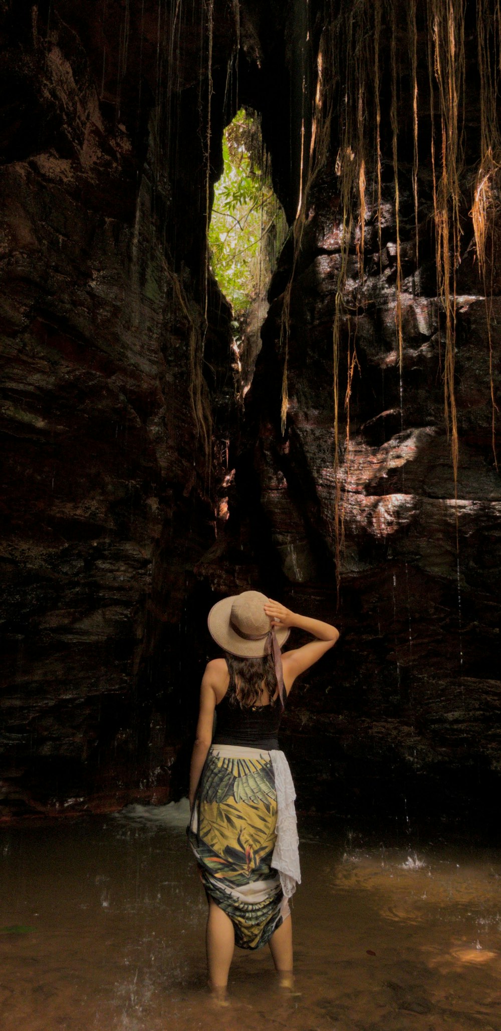 topless woman in black shorts sitting on rock