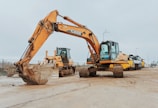 yellow excavator on gray concrete road during daytime