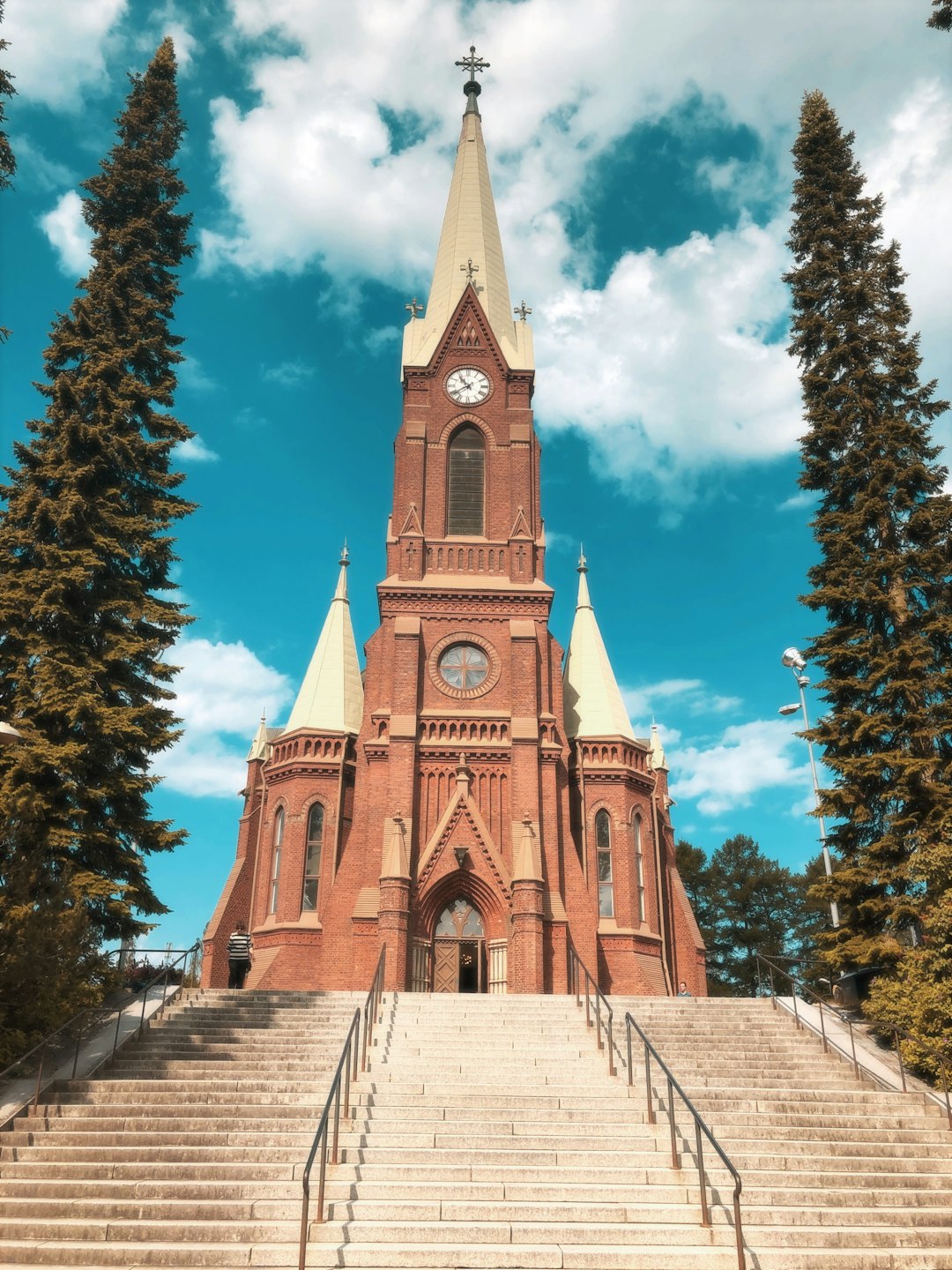 white and brown concrete church near green trees under blue sky during daytime