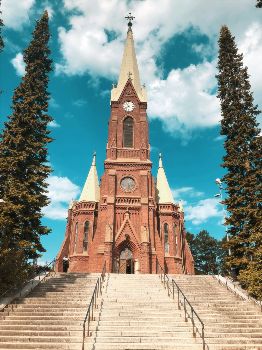 white and brown concrete church near green trees under blue sky during daytime