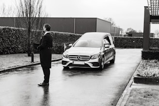 man in black jacket standing beside silver mercedes benz car