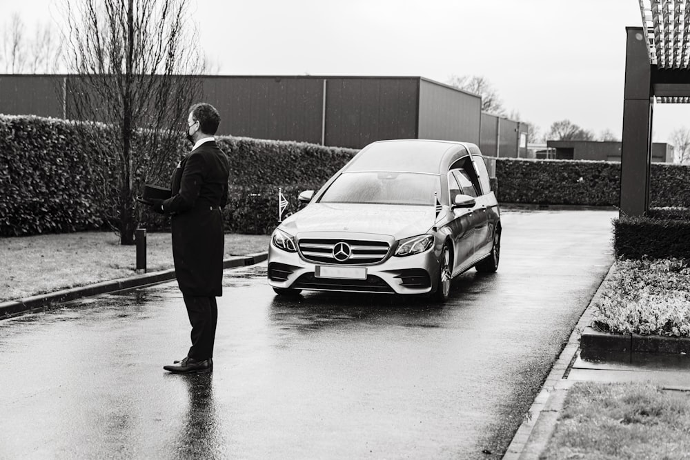 man in black jacket standing beside silver mercedes benz car