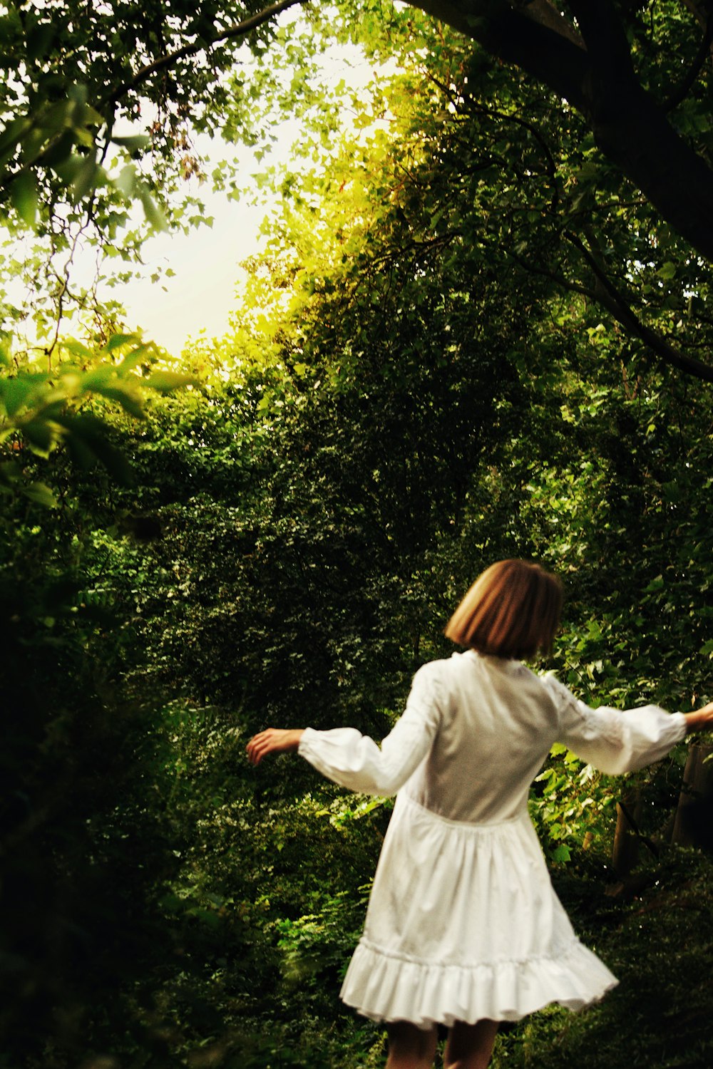 woman in white long sleeve shirt standing on green grass field during daytime