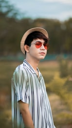 man in white and blue striped collared shirt wearing brown fedora hat