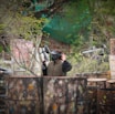 man in black jacket and black cap sitting on brown wooden bench