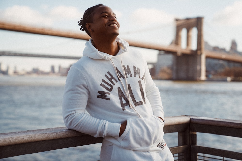 man in white hoodie sitting on brown wooden bench during daytime