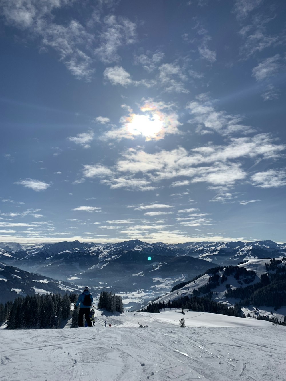 person standing on snow covered ground under blue sky and white clouds during daytime