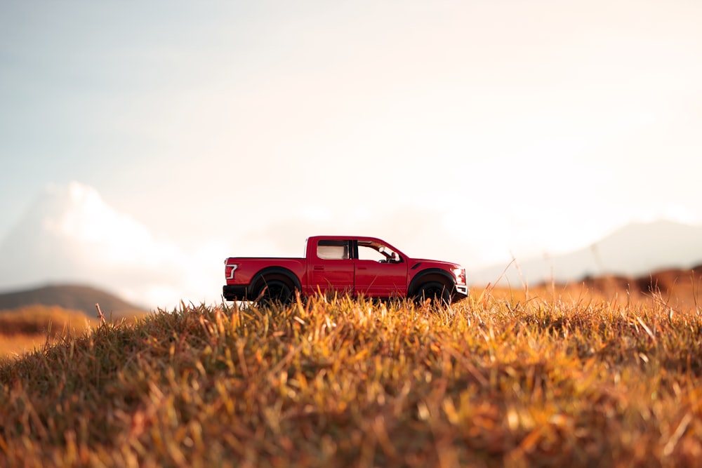 茶色の芝生の上の赤いシングルキャブピックアップトラック