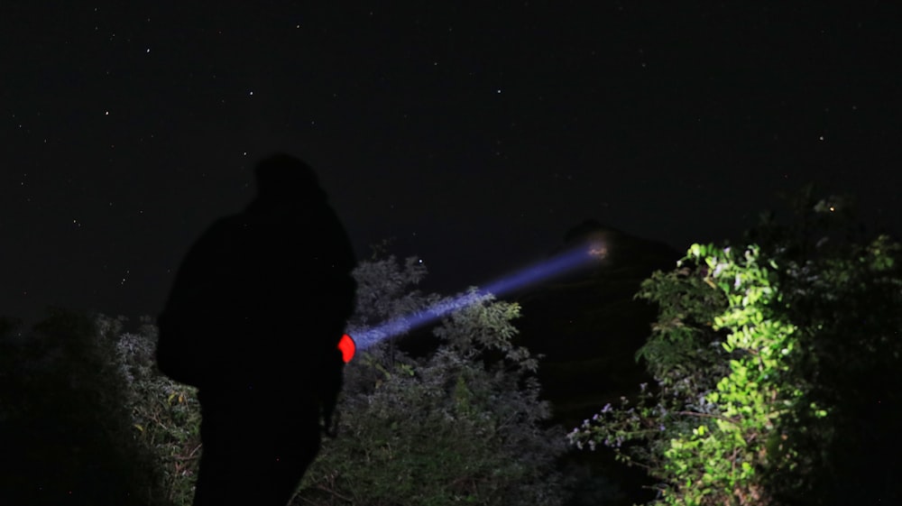 man in black jacket standing on green grass field during night time