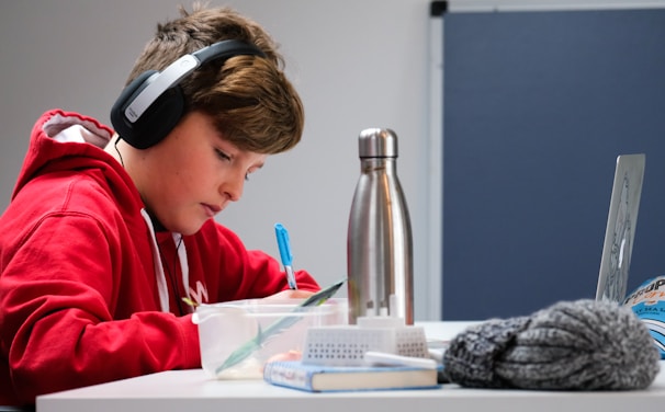A focused learner writing a detailed study plan in a notebook, surrounded by colorful markers and sticky notes.