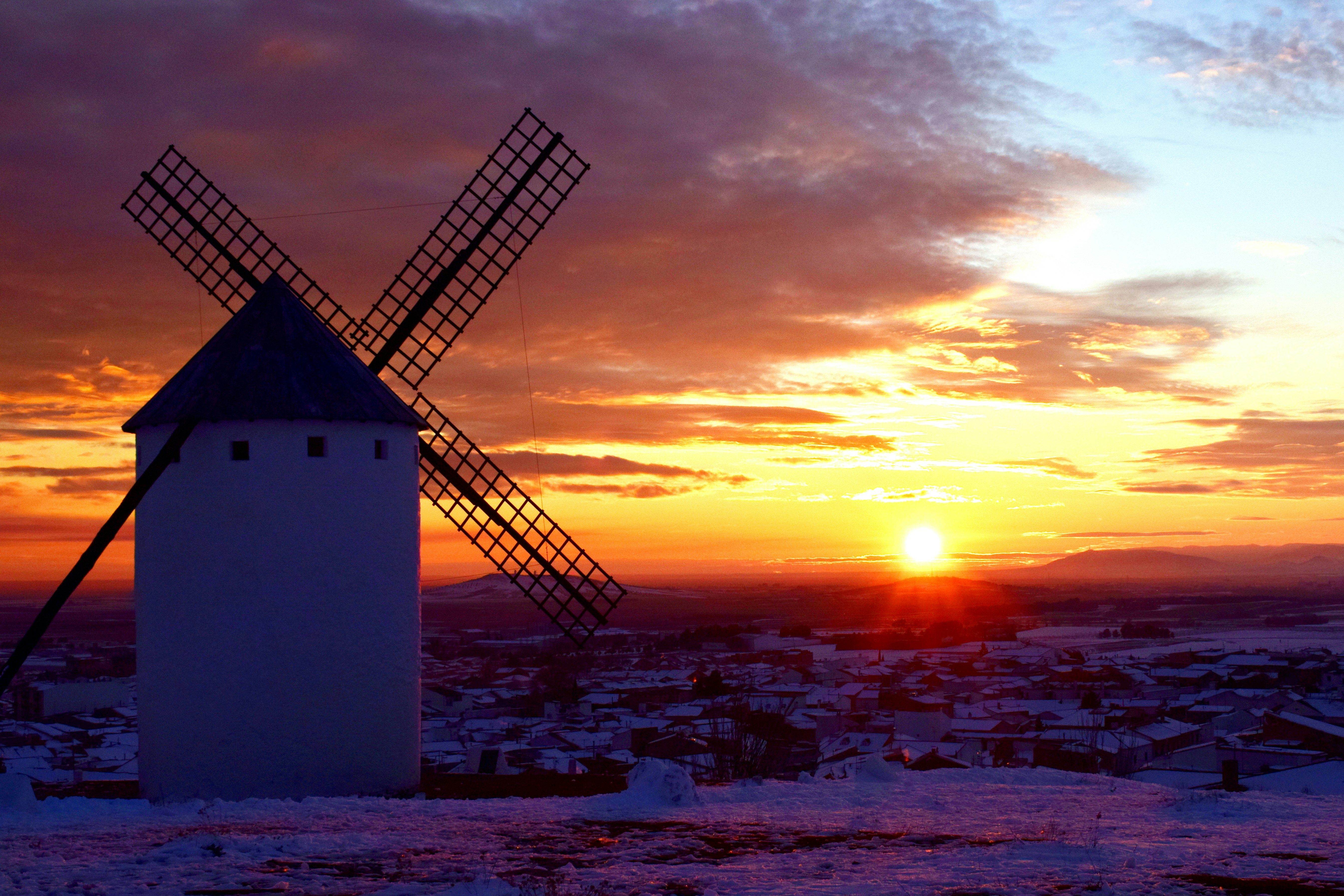 Puesta de sol en los molinos de viento de Campo de Criptana, nevada, Ciudad Real, España