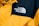 A close-up of a jacket featuring a prominent logo of 'The North Face' embroidered in white on a contrasting black section of fabric. The majority of the jacket is bright yellow with details such as buttons and stitching visible.