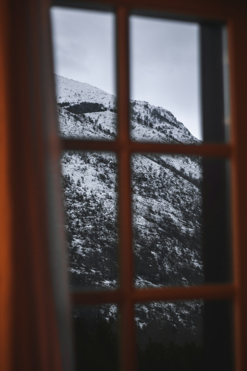 black metal window frame with snow covered mountain in distance