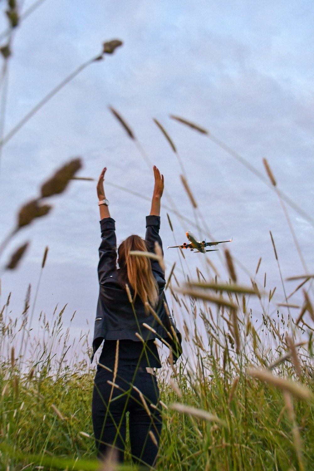 woman in black jacket standing on green grass field during daytime