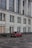 red car parked beside white concrete building during daytime