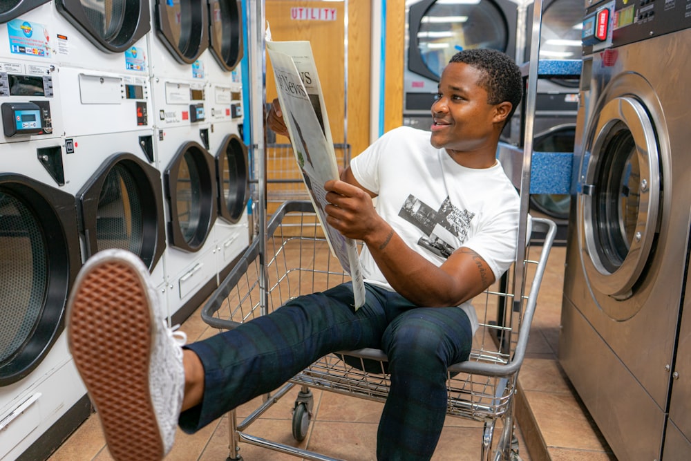 man in white crew neck t-shirt sitting on stainless steel shopping cart