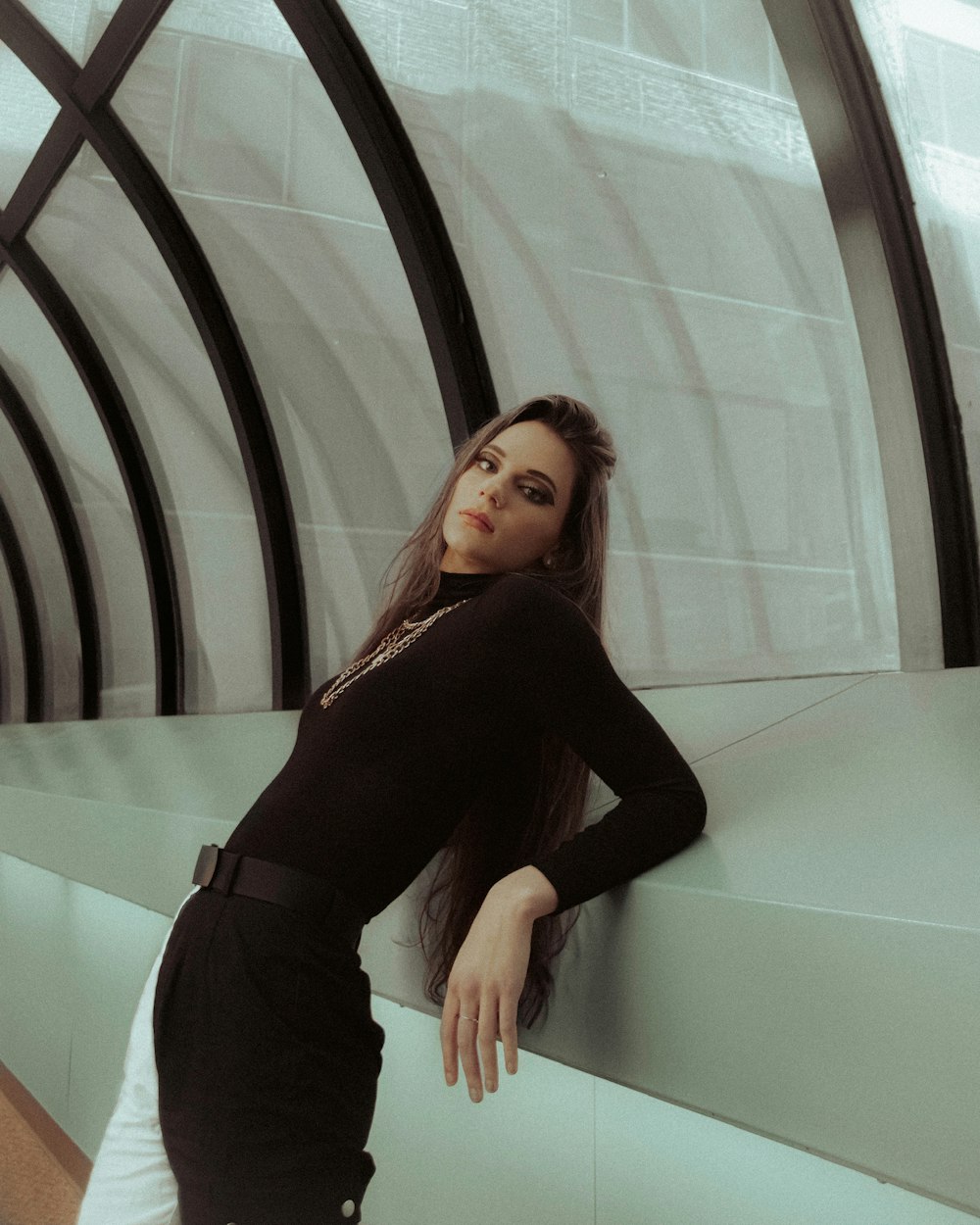 woman in black long sleeve shirt and black pants standing beside glass wall