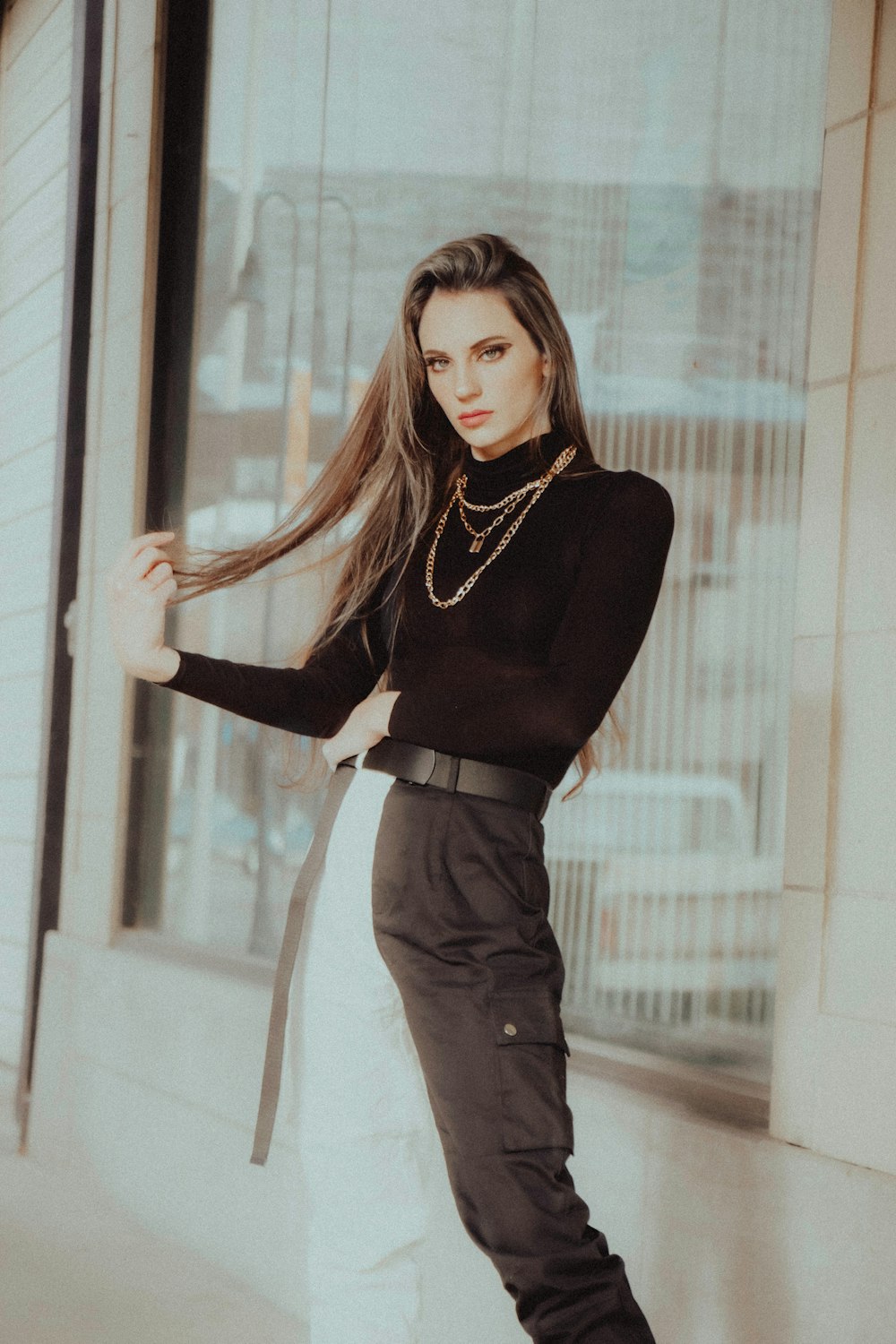 woman in black long sleeve shirt and gray pants standing beside glass window