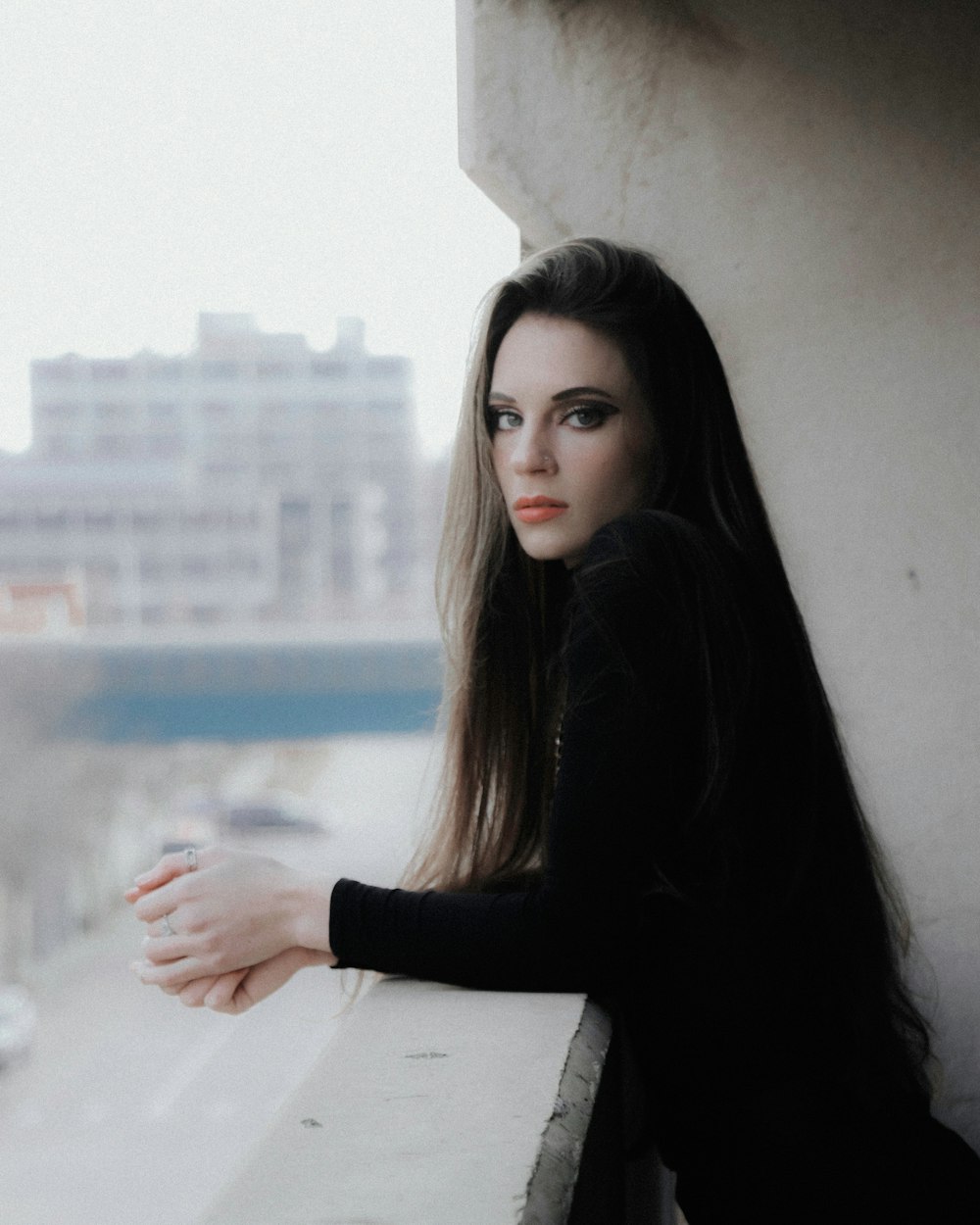 woman in black long sleeve shirt leaning on white wall